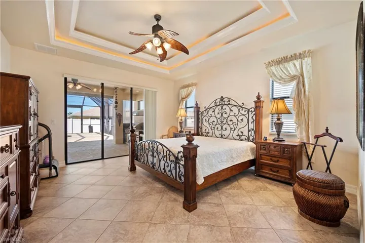 Bedroom with ceiling fan, access to exterior, multiple windows, light tile patterned floors, and ornamental molding