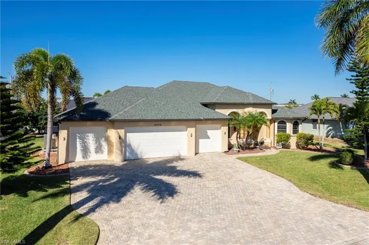 View of front of property featuring an attached garage, a front lawn, stucco siding, driveway, and roof with shingles