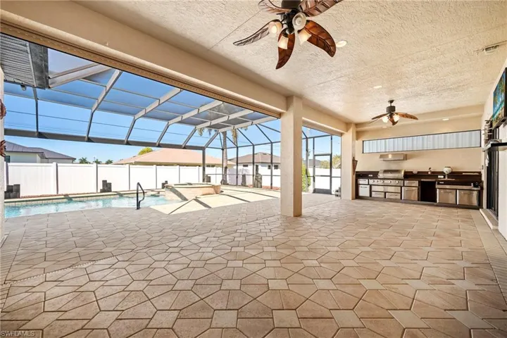 Fenced backyard featuring an outdoor kitchen, a patio area, a sunroom, a lanai, and ceiling fan