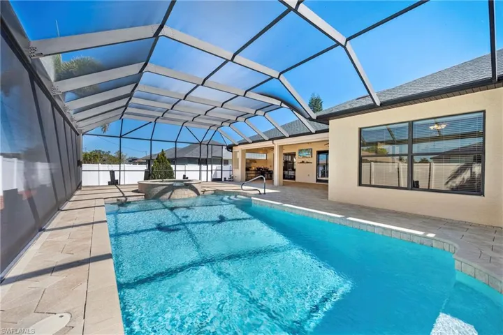 Integrated pool / spa featuring a sunroom, a patio, and glass enclosure