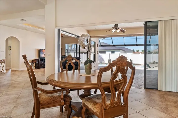 Dining space featuring arched walkways, light tile patterned floors, and a ceiling fan