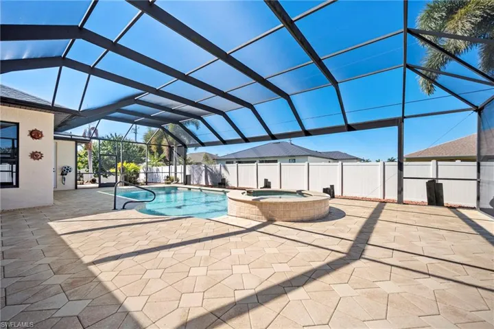 Combined pool / hot tub with a sunroom, a lanai, a patio, and a fenced backyard