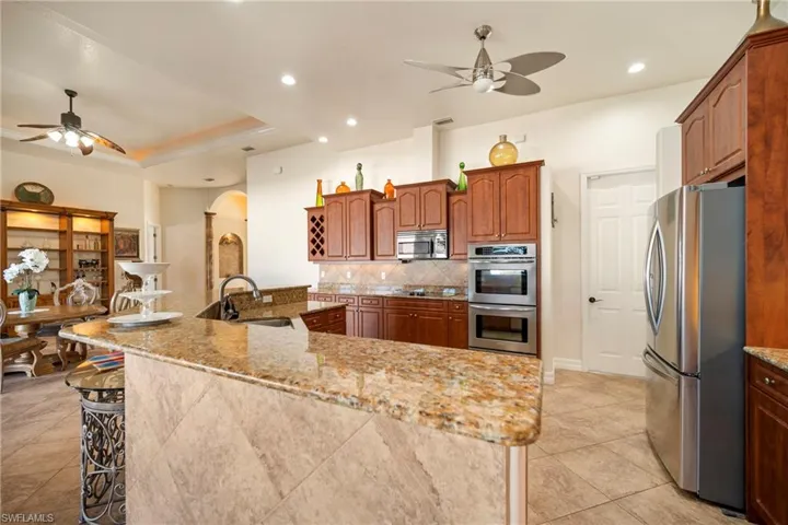 Kitchen with a ceiling fan, a spacious island, stainless steel appliances, arched walkways, and recessed lighting