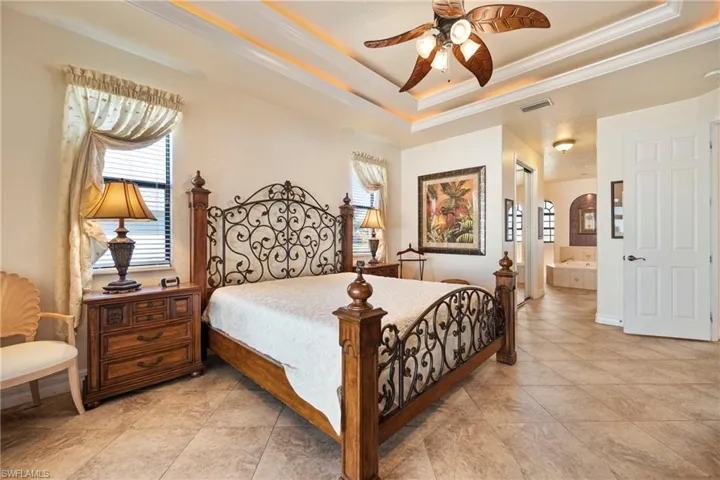 Bedroom featuring crown molding, multiple windows, a ceiling fan, ensuite bathroom, and light tile patterned floors
