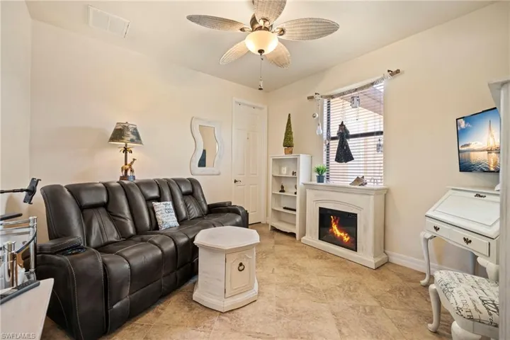 Living area featuring ceiling fan and a glass covered fireplace