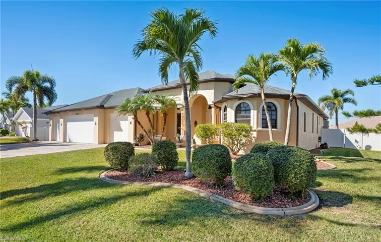 Mediterranean / spanish house with an attached garage, a front lawn, driveway, and stucco siding