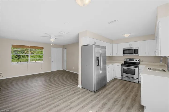 Kitchen featuring stainless steel appliances, light wood finished floors, open floor plan, light countertops, and a ceiling fan