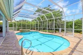 View of pool with an in ground hot tub, a patio area, and glass enclosure