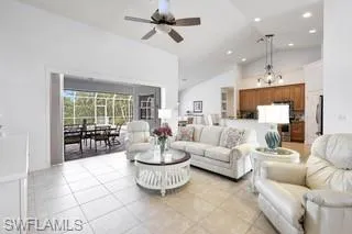 Tiled living room with high vaulted ceiling and ceiling fan with notable chandelier