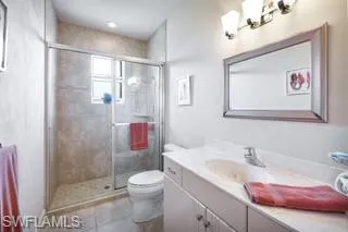 Bathroom with vanity, tile patterned flooring, toilet, and an enclosed shower