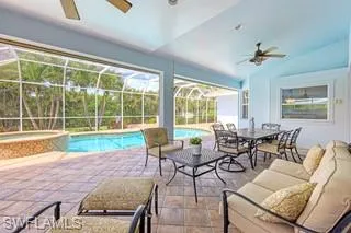 View of pool with a patio area, ceiling fan, and glass enclosure
