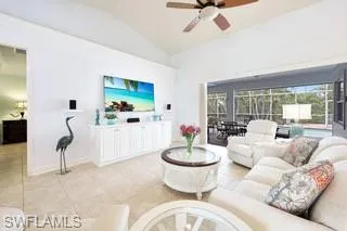 Living room featuring light tile patterned floors, vaulted ceiling, and ceiling fan