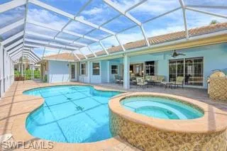 View of pool with an in ground hot tub, ceiling fan, glass enclosure, and a patio