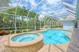 View of swimming pool with an in ground hot tub, a patio, and glass enclosure