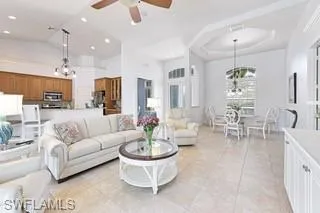 Tiled living room featuring lofted ceiling and ceiling fan with notable chandelier