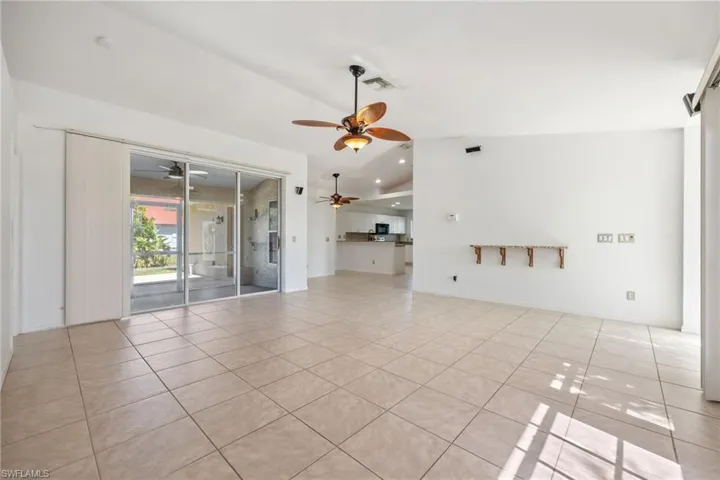 Unfurnished living room featuring lofted ceiling, light tile patterned floors, and a ceiling fan
