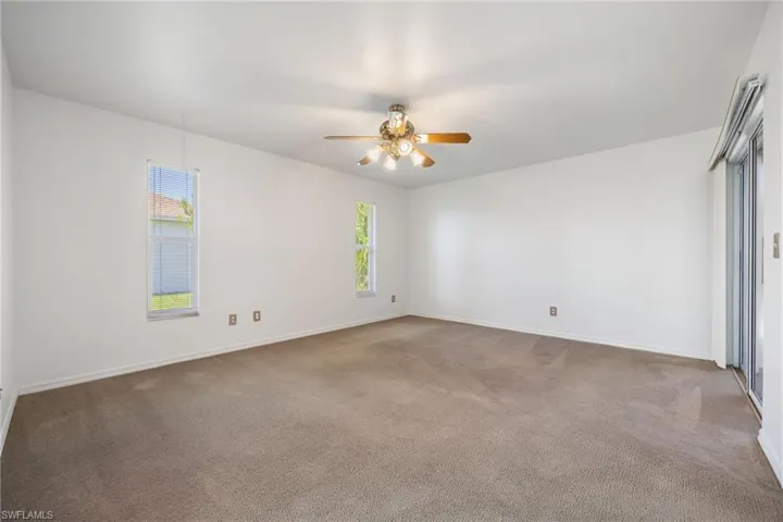 Empty room featuring light colored carpet and ceiling fan