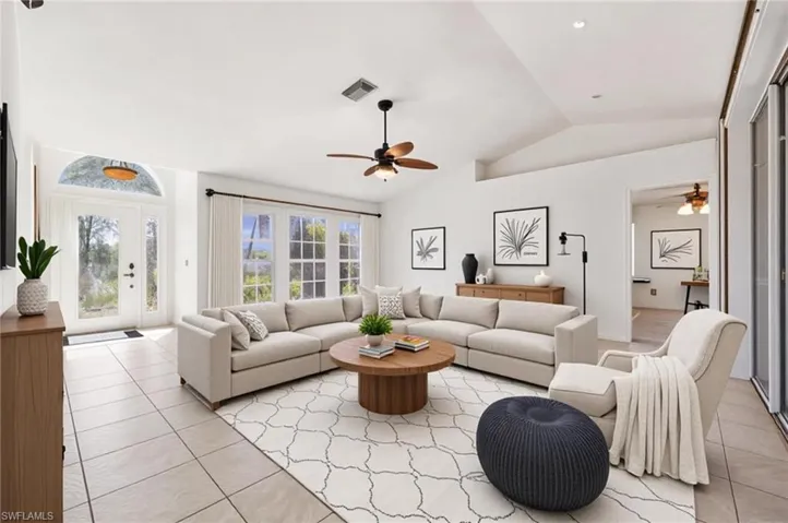 Living area with lofted ceiling, a ceiling fan, and light tile patterned flooring