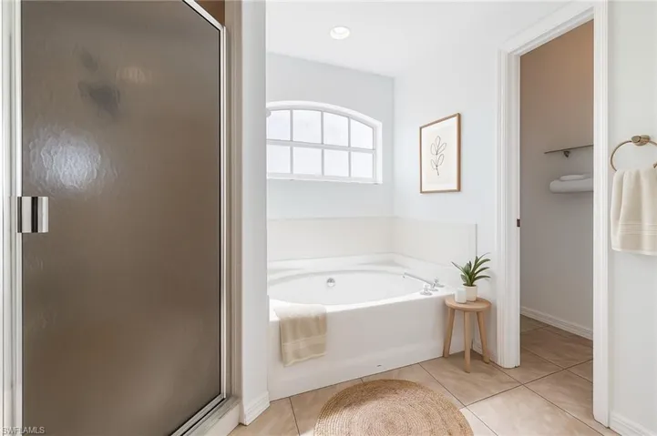 Bathroom featuring light tile patterned flooring, a garden tub, and a stall shower