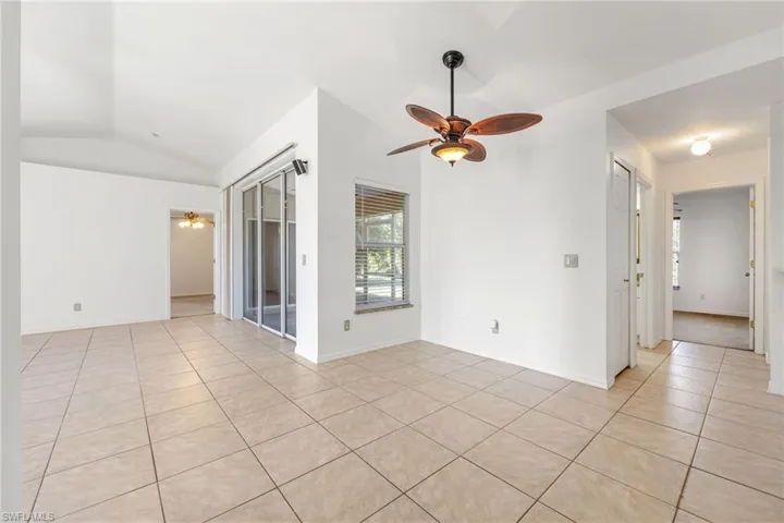 Unfurnished room featuring a ceiling fan, light tile patterned floors, and lofted ceiling