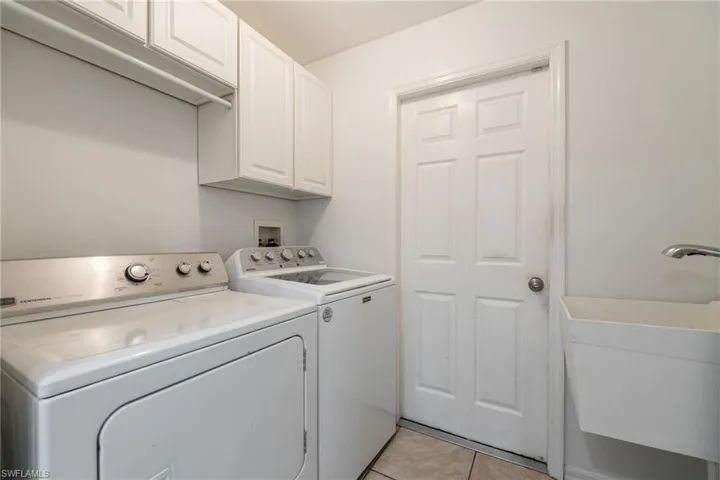 Washroom featuring light tile patterned floors, washer and dryer, and cabinet space