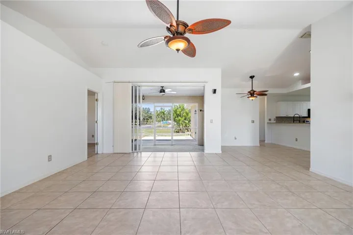 Unfurnished room with lofted ceiling, light tile patterned floors, and a ceiling fan