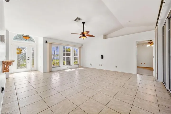 Unfurnished living room with light tile patterned floors, vaulted ceiling, and a ceiling fan