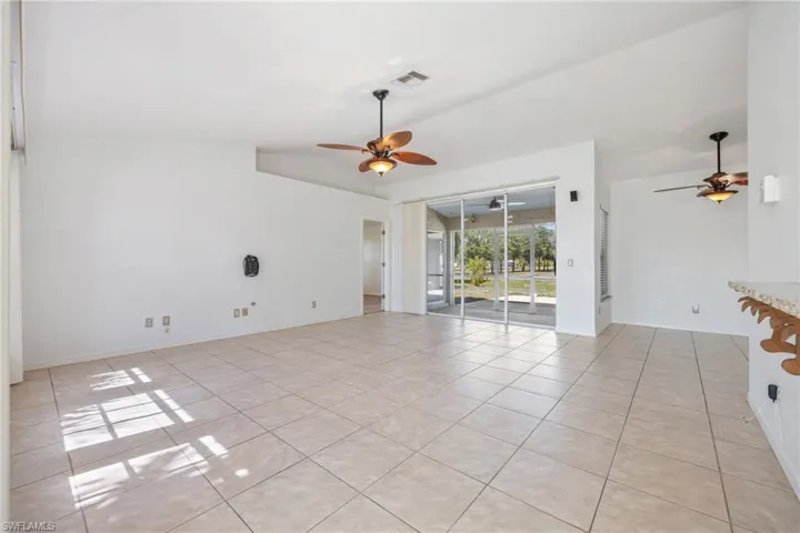 Spare room featuring vaulted ceiling, light tile patterned flooring, and ceiling fan
