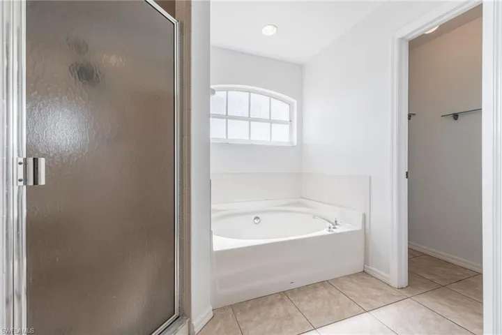 Full bathroom featuring a garden tub, light tile patterned floors, and a shower stall