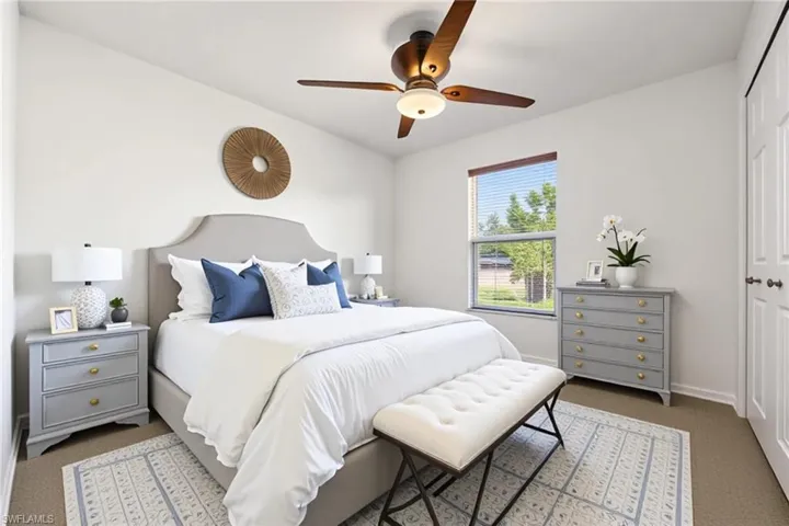 Carpeted bedroom with ceiling fan and a closet