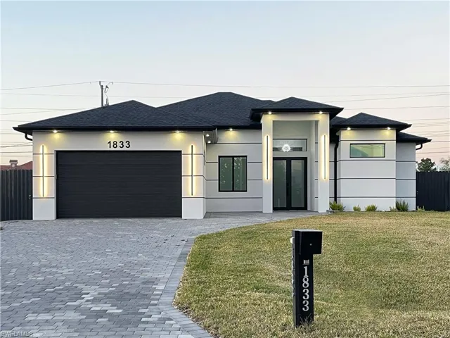 View of front of house featuring an attached garage, roof with shingles, decorative driveway, and stucco siding