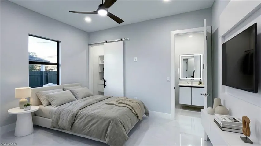 Bedroom with a barn door, a walk in closet, a ceiling fan, recessed lighting, and ensuite bathroom