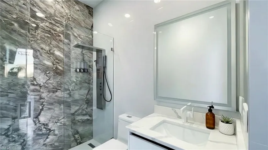 Full bathroom featuring a marble finish shower and vanity