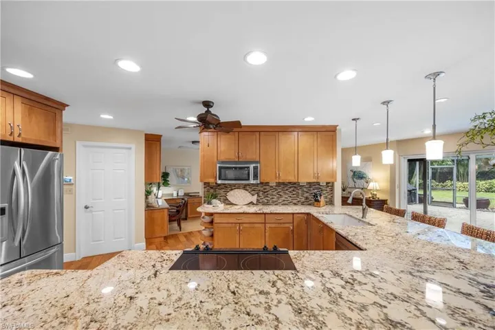 Kitchen featuring decorative light fixtures, light hardwood / wood-style floors, stainless steel appliances, sink, and ceiling fan
