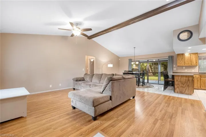 Living room with laminate flooring, a cathedral ceiling & charming wood beam