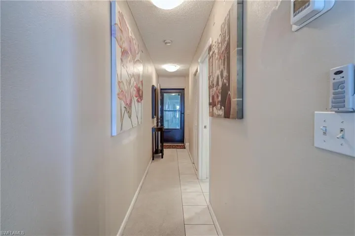 Hall featuring a textured ceiling and light tile patterned floors
