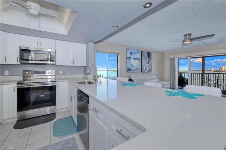 Kitchen with ceiling fan, stainless steel appliances, white cabinets, a textured ceiling, and light tile patterned floors