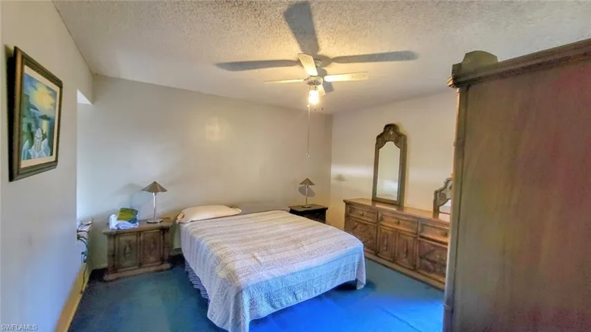 Bedroom with ceiling fan, carpet floors, and a textured ceiling