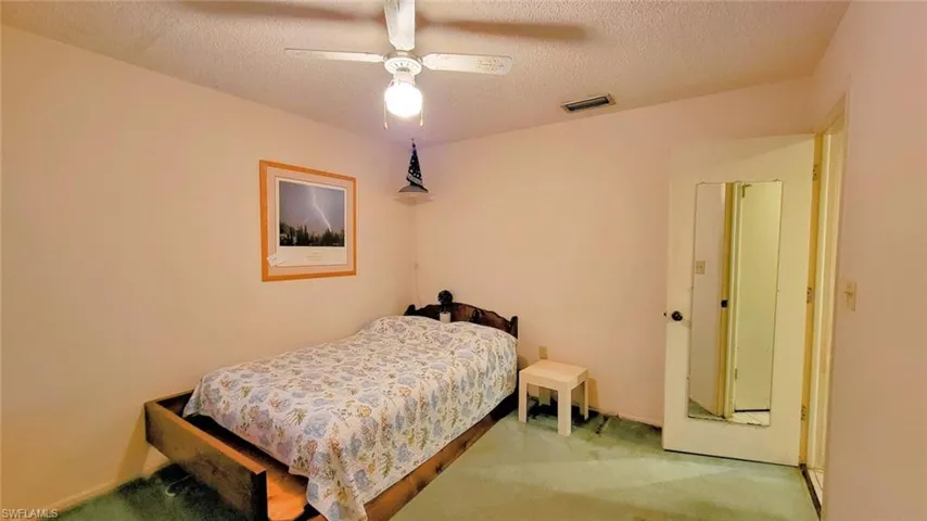 Bedroom with ceiling fan, carpet floors, and a textured ceiling