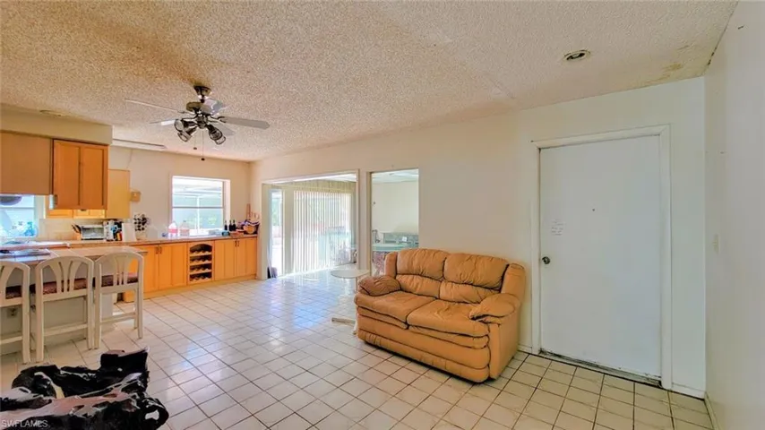 Living room featuring a textured ceiling, light tile flooring, and ceiling fan