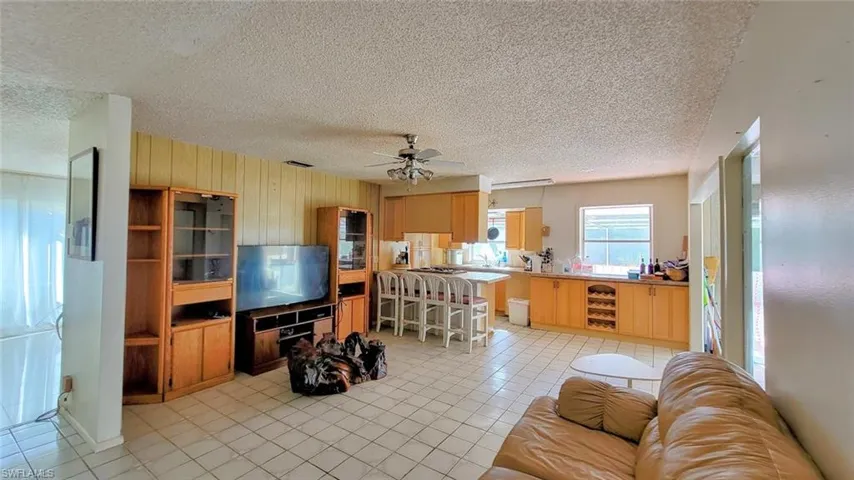 Living room featuring wine cooler, a textured ceiling, ceiling fan, and light tile floors