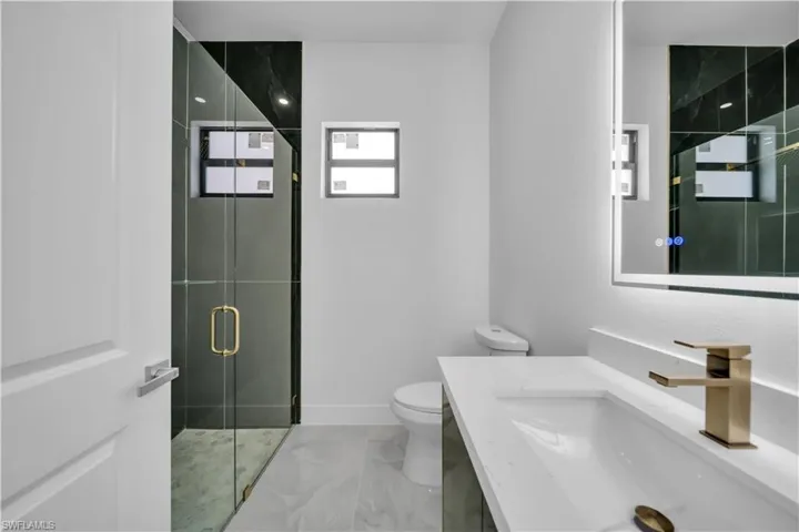 Full bath with a stall shower, vanity, and light marble finish floors