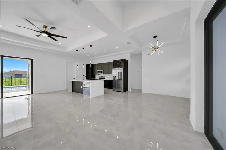 Unfurnished living room featuring coffered ceiling, a chandelier, beam ceiling, recessed lighting, and ceiling fan
