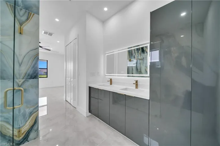 Bathroom with light marble finish flooring, a marble finish shower, double vanity, recessed lighting, and a ceiling fan
