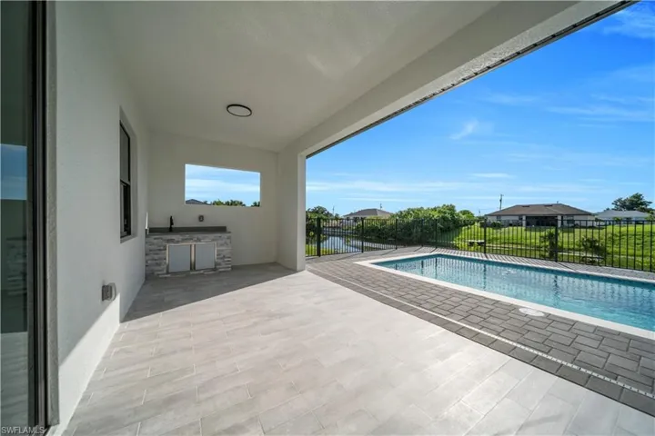 View of pool featuring exterior kitchen, a patio area, and a residential view