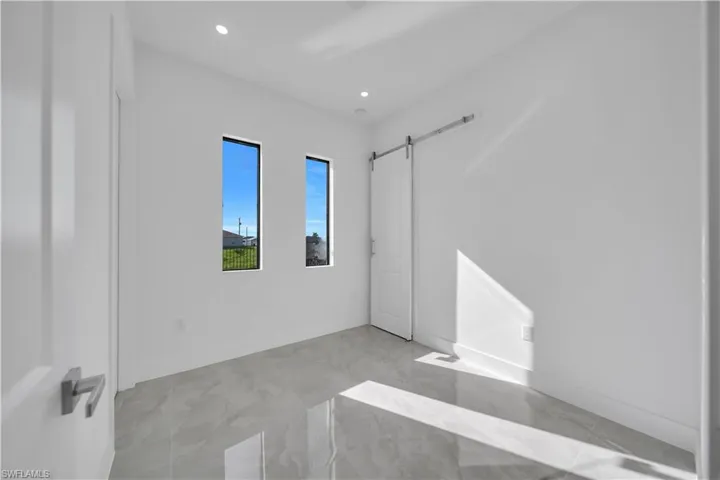 Unfurnished bedroom featuring a barn door and recessed lighting