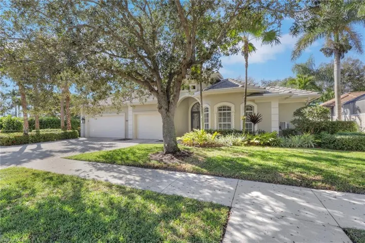 View of front of property featuring a front lawn, stucco siding, concrete driveway, and a tile roof