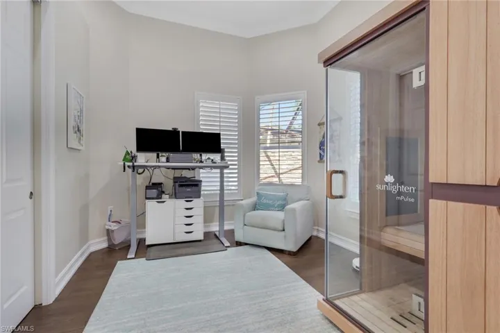 Home office with a sauna, dark wood-type flooring, and ornamental molding
