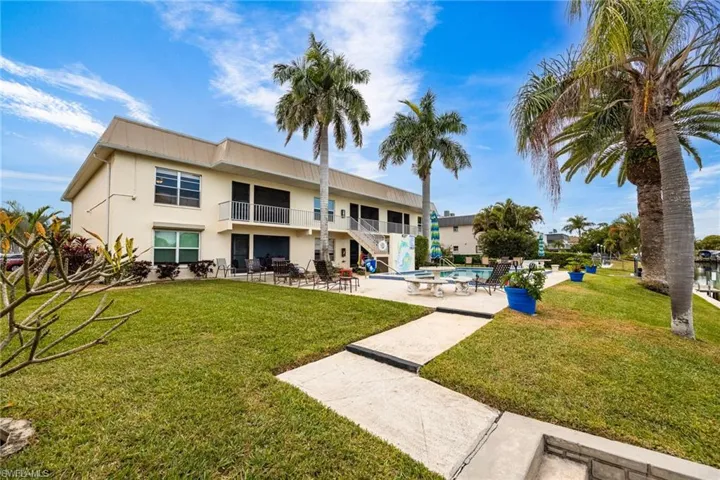 Rear view of property with a patio area, a balcony, stucco siding, and a lawn