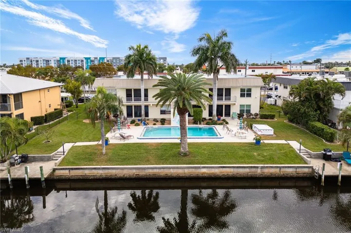 Back of property featuring a patio, a yard, stucco siding, and a water view